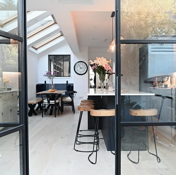 Steel-framed doors opening onto a kitchen extension with rooflights and a dining banquette