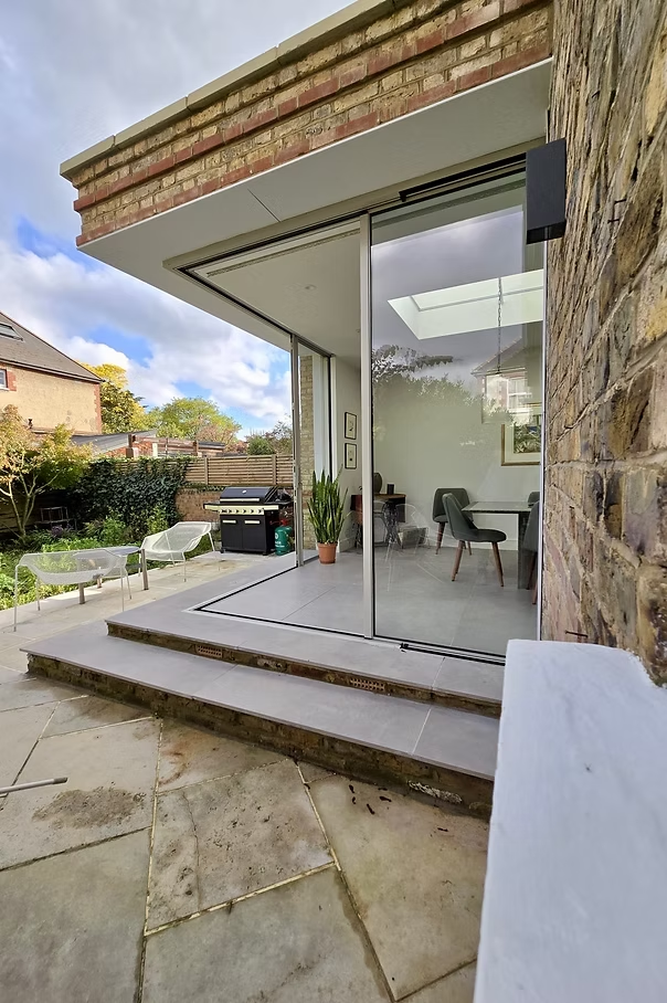 Rear extension with sliding glass doors opening onto a paved garden terrace