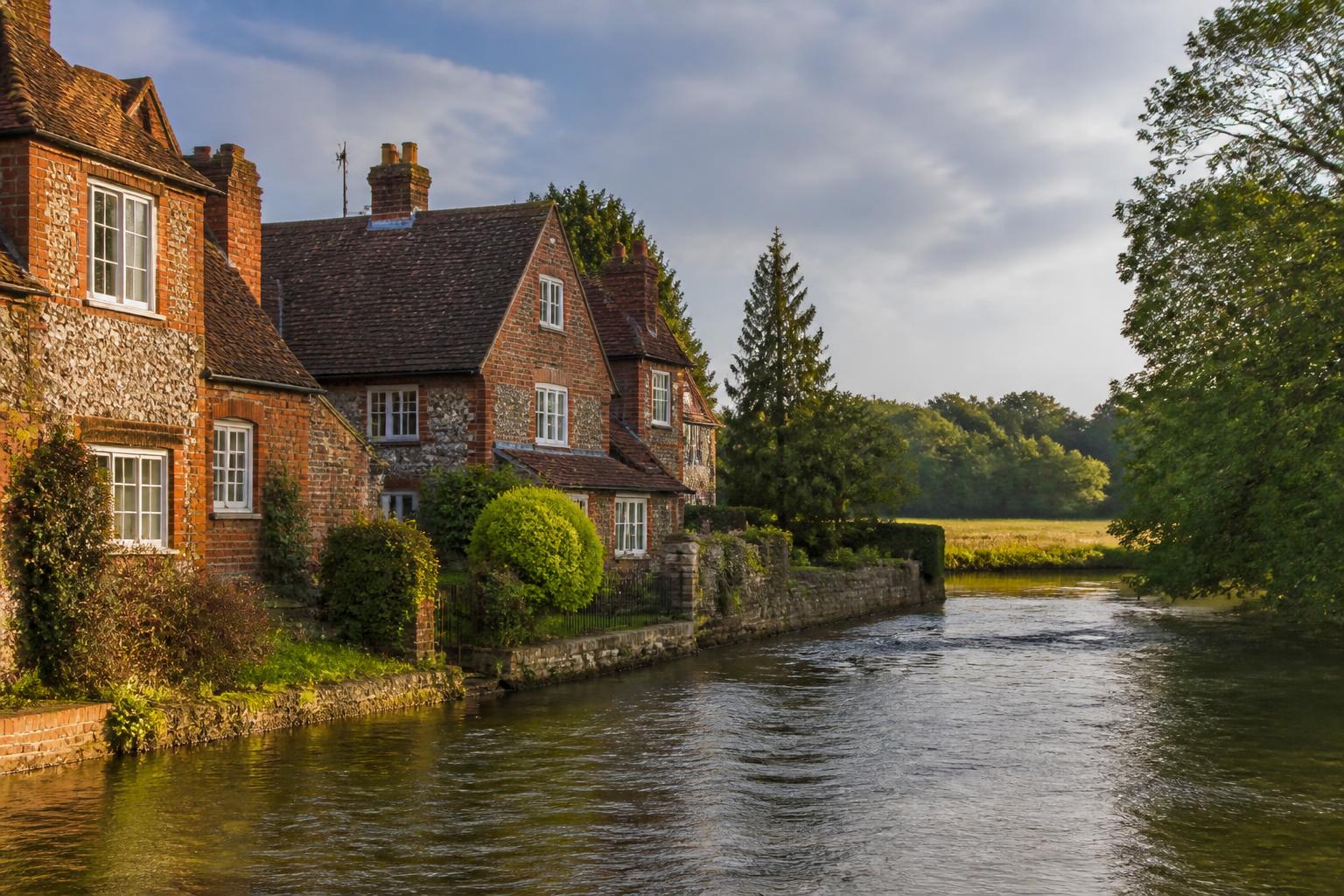 Berkshire brick and flint riverside cottages beside the Thames with open fields beyond