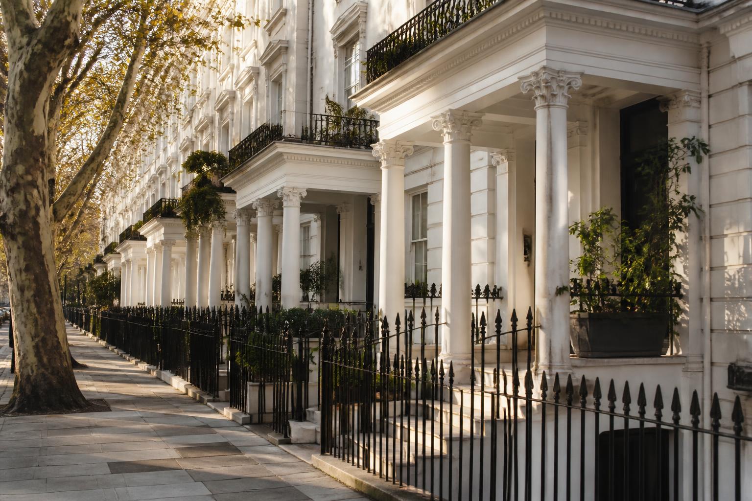 White stucco-fronted West London townhouses with pillared porches and black railings